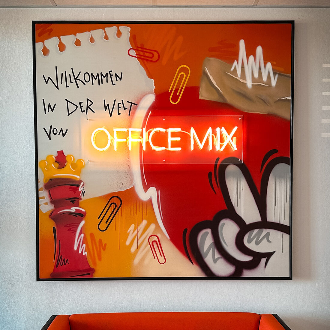 Mixtechnik in den Farben von Office Mix (Rottöne, Gelb und Orange), verschiedene Büroartikel als Details im Fokus, das Logo als Leuchtinstallation/Neonröhre.