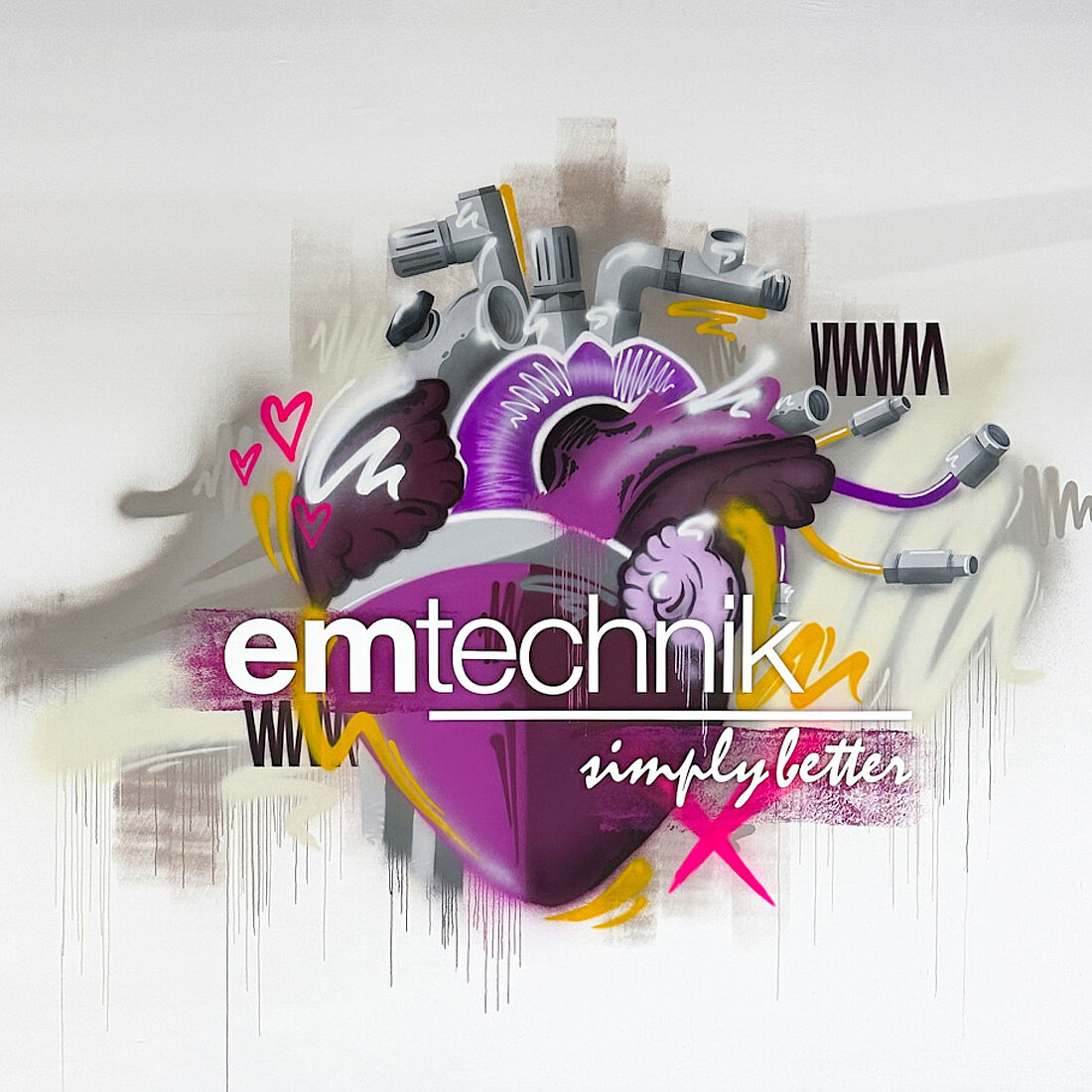 Ein anatomisches Herz, bestückt mit Produkten (Armaturen und Verschraubungen) von emtechnik. Der Logoschriftzug ist als Acrylinstallation integriert.