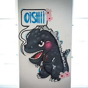 Artwork von einem kleinen Godzilla mit Sprechblase mit den Worten Oishii